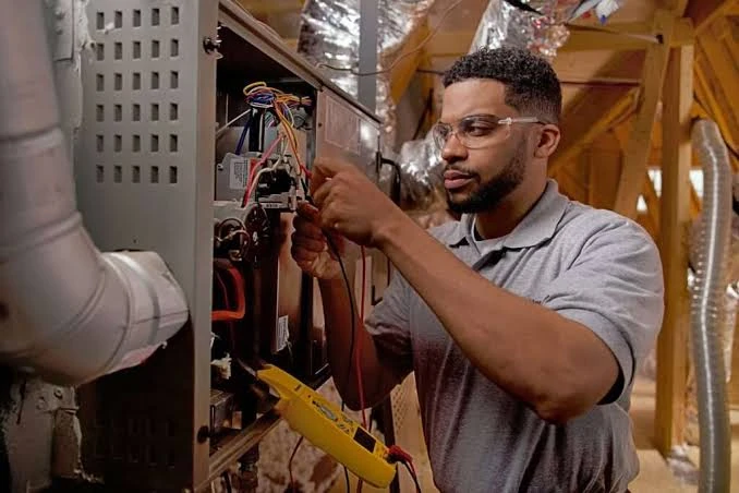 Technician repairing wiring inside a residential furnace